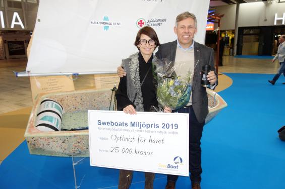 Branschorganisationen Sweboats miljöfond delande ut 25 000 kronor till projekt Optimist. Optimistjollen är byggd av plastskräp som samlats in från strandstädningar. Sharon Emanuel från Håll Sverige Rent och Thomas Hansson-Mild från Svenska seglarförbundet tog emot checken.